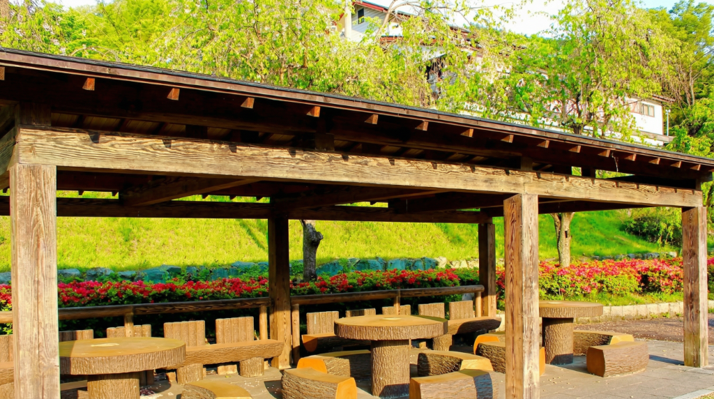 Sサイト 東屋の様子 — 木製の東屋とテーブル・イスが緑に囲まれた風景